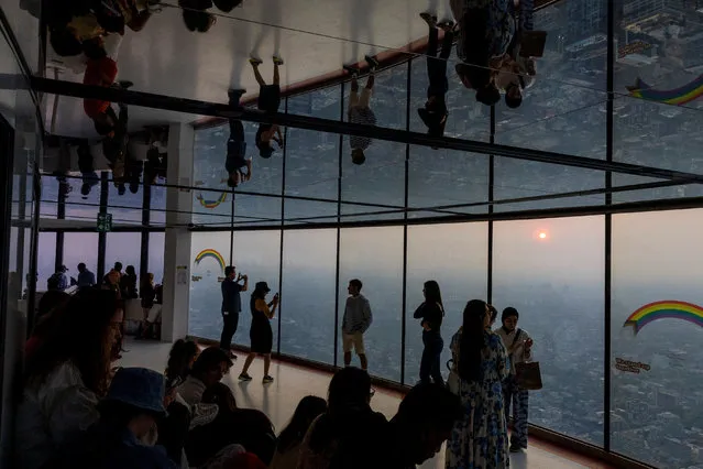 People take photographs as a smokey Toronto is seen from the CN Tower as wildfires in Ontario and Quebec continue to burn, in Toronto, Ontario, Canada on June 6, 2023. (Photo by Carlos Osorio/Reuters)