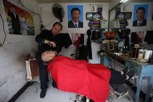 A barber shaves the face of his customer next to posters of Chinese President Xi Jinxing and his wife Peng Liyuan, at his barber shop in Yongjia county, Zhejiang province January 29, 2015. (Photo by William Hong/Reuters)