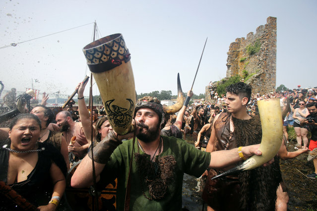 A participant dressed as a Viking blows a horn as he takes part in the annual Viking festival of Catoira in north-western Spain on August 5, 2018. (Photo by Miguel Vidal/Reuters)