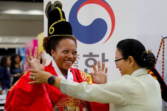 Attendee Denisha tries on a traditional Korean costume at KCON USA, billed as the world's largest Korean culture convention and music festival, in Los Angeles, California on August 11, 2018. Many Americans were given their first taste of K-pop via the viral success of rapper Psy's music video “Gangnam Style” in 2012. This year, another Korean act's growing fan base in the United States has K-pop stars, including some who grew up in America, thinking they too could win fame in the United States. (Photo by Mike Blake/Reuters)