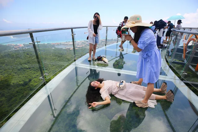 Tourists pose for photos on a sightseeing platform of a 400-meter-long glass-bottomed skyway at the Yalong Bay Tropical Paradise Forest Park in Sanya city, Hainan province, China on September 3, 2018. A 400-meter glass walkway in Yalong Bay Tropical Paradise Forest Park in Sanya, Hainan Province opened to the public at the end of August and became a popular tourist spot immediately. The park is located in the southeast of Sanya and surrounds the Yalong Bay National Tourist Resort, known as the most spectacular bay in the world because of its natural assets. (Photo by Imaginechina/Rex Features/Shutterstock)