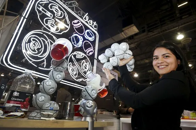 Anita Santa-Coloma holds up a CellRobot by KEYi Technology during the 2016 CES trade show in Las Vegas, Nevada January 8, 2016. The modular entertainment robots can be assembled in various configurations. The robots at left are mixing drinks. The robot will cost between $250-600 depending on the kit, Santa-Coloma said. (Photo by Steve Marcus/Reuters)