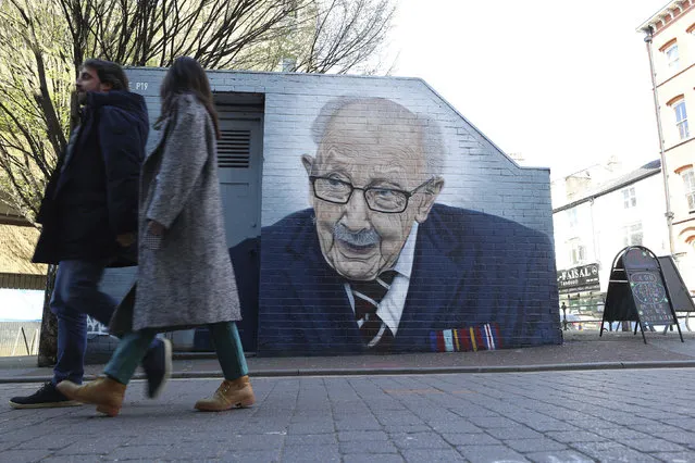 People walk past a mural of Captain Tom Moore by by street artist Akse P19 in Manchester's North Quarter, England, Friday April 2, 2021. (Photo by Peter Byrne/PA Wire via AP Photo)