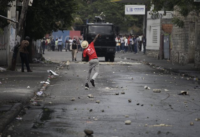 A demonstrator throws a rock at a water cannon police vehicle during protests near Champs de Mars in Port-au-Prince, Haiti February 13, 2015. Anti-government street protesters took to the streets of Port-au-Prince again on Friday  as the country plunged deeper into political and economic crises even as many prepared for the annual Carnival, normally a time of peaceful revelry. (Photo by Andres Martinez Casares/Reuters)