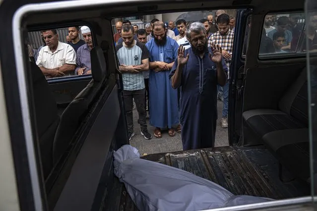 Relatives pray by the body of a person killed in an Israeli air strike in Gaza City on Monday, October 9, 2023. Israel's military battled to drive Hamas fighters out of southern towns and seal its borders Monday as it pounded the Gaza Strip. (Photo by Fatima Shbair/AP Photo)