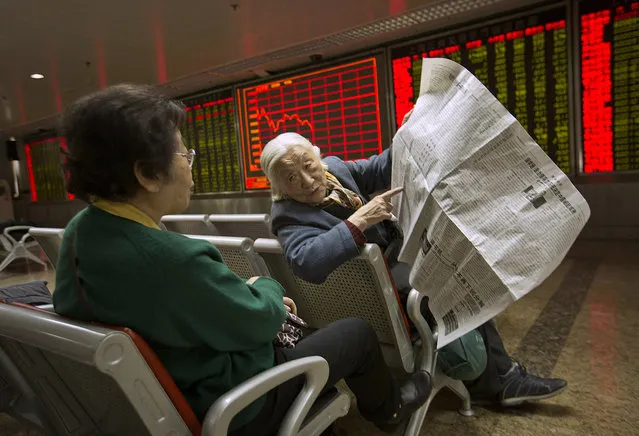 Chinese stock investors look over a newspaper in a brokerage house in Beijing, Wednesday, January 27, 2016. Chinese stocks sank again Wednesday but other Asian markets rose following Wall Street's gain as investors looked ahead to the U.S. Federal Reserve's latest statement on interest rates and the economic outlook. (Photo by Mark Schiefelbein/AP Photo)