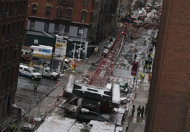 Emergency responders respond to the scene of a 565-foot-tall crane that toppled and flipped upside down, stretching along nearly two city blocks in downtown Manhattan in New York, February 5, 2016. The massive construction crane collapsed in lower Manhattan during a swirling snowstorm on Friday, killing one person and crushing a line of parked cars in the first accident of its kind in New York City since 2008. (Photo by Brendan McDermid/Reuters)