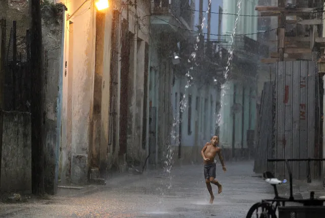 A boy dances in the rain during a heavy tropical shower in a street of Havana, July 2010. (Photo by Desmond Boylan/Reuters)