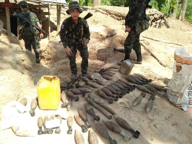 In this photo provided by Karen National Liberation Army, a Karen National Liberation Army soldier holds a motor shell while standing next to a cache of mortar shells found at a Myanmar military outpost Friday, May 7, 2021, in Mutraw district, Karen State, Myanmar. Ethnic Karen guerrillas burned down a Myanmar military outpost Friday morning, capturing it without a fight after its garrison fled at their approach, a senior Karen officer said. (Photo by Karen National Liberation Army via AP Photo)