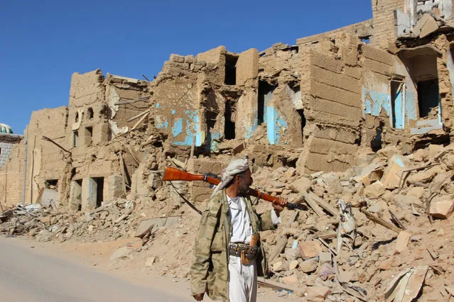A Houthi armed man walks past destroyed houses in the old quarter of the northwestern city of Saada, Yemen January 11, 2017. (Photo by Naif Rahma/Reuters)