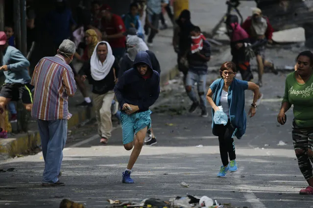 Anti-government protesters run during clashes with security forces as they show support for an apparent mutiny by a national guard unit in the Cotiza neighborhood of Caracas, Venezuela, Monday, January 21, 2019. (Photo by Ariana Cubillos/AP Photo)