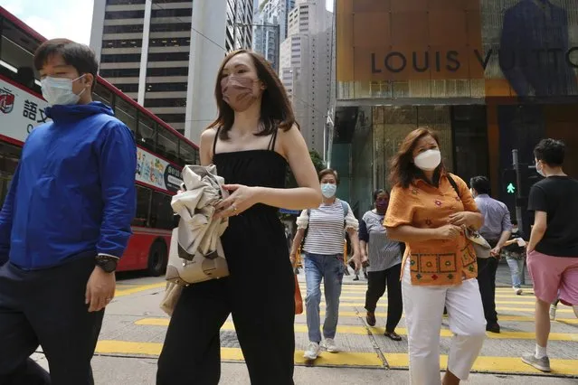 People wearing face masks to prevent the spread of coronavirus walk on a downtown street in Hong Kong, Tuesday, August 17, 2021. Hong Kong will tighten entry restrictions for travelers arriving from the United States and 14 other countries from Friday, increasing the quarantine period to 21 days. (Photo by Vincent Yu/AP Photo)