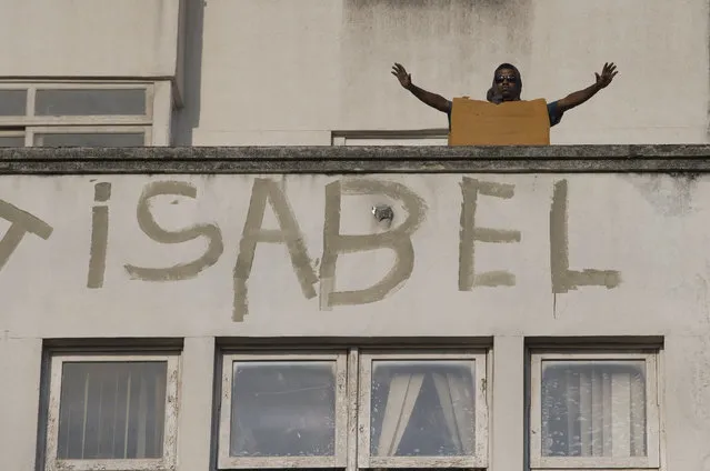 A squatter wearing foam for protection raises his arms as police stand below, during an eviction from the building people invaded about a week ago in the Flamengo neighborhood of Rio de Janeiro, Brazil, Tuesday, April 14, 2015. (Photo by Silvia Izquierdo/AP Photo)