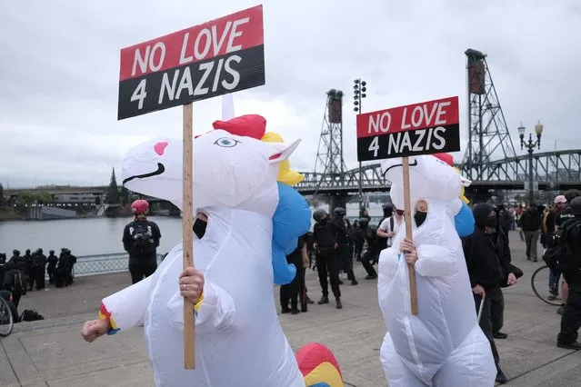 Anti-fascist protesters dressed as unicorns hold signs as people gather on the waterfront to demonstrate against a Proud Boy rally on Sunday, August 22, 2021, in Portland, Ore. (Photo by Alex Milan Tracy/AP Photo)