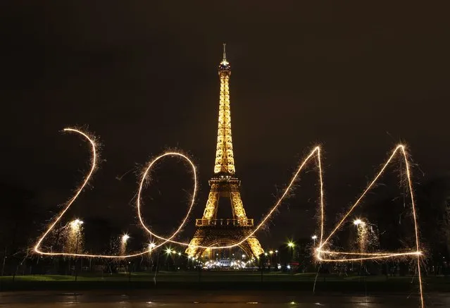 A reveler writes “2014” with sparklers ahead of New Year's Eve, in front of the Eiffel Tower in Paris. (Photo by Benoit Tessier/Reuters)