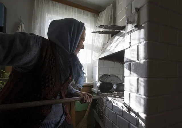 Nastia Pokolo, 74, puts a pot into a furnace at her house in the village of Babinets, southwest of the capital Minsk, April 17, 2015. (Photo by Vasily Fedosenko/Reuters)