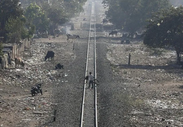 A man carries his bicycle as he crosses a railway track in Ahmedabad, India, February 24, 2016. India's federal-run railways will have to depend on more government support and borrowing to fix their finances in its budget on Thursday, with New Delhi reluctant to unveil steep fare hikes ahead of key state elections, officials said. (Photo by Amit Dave/Reuters)
