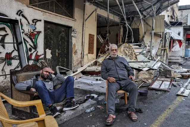 Palestinian men sit by debris outside a damaged building in the aftermath of an Israeli raid in the Nur Shams camp for Palestinian refugees near the northern city of Tulkarm in the occupied West Bank on December 27, 2023. The Israeli operation in the Palestinian refugee camp in the north of the occupied West Bank left six people dead and several others wounded according to the Palestinian ministry of health. According to the official Palestinian news agency Wafa, the six people were killed by Israeli air strikes on the refugee camp where Israeli soldiers were also deployed. (Photo by Zain Jaafar/AFP Photo)