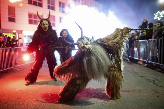 A participant wearing a traditional Krampus costume and a mask performs during a Krampus run in Hollabrunn, Austria, Sunday, November 26, 2022. (Photo by Michael Gruber/AP Photo)