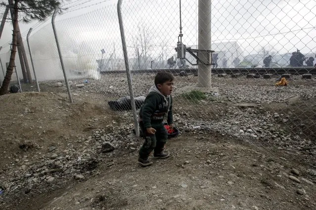 A boy reacts from tear gas fired by the Macedonian police at stranded refugees and migrants who tried to bring down part of the border fence during a protest at the Greek-Macedonian border, near the Greek village of Idomeni, February 29, 2016. (Photo by Alexandros Avramidis/Reuters)