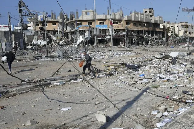 Palestinians walk through destruction by the Israeli bombardment in the Nusseirat refugee camp in Gaza Strip, Tuesday, January 16, 2024. (Photo by Adel Hana/AP Photo)