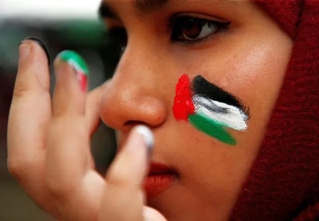 A woman with colours of the Palestinian flag painted on her cheek takes part in a solidarity gathering in support of Palestinians in Kuala Lumpur, Malaysia on October 13, 2023. (Photo by Hasnoor Hussain/Reuters)