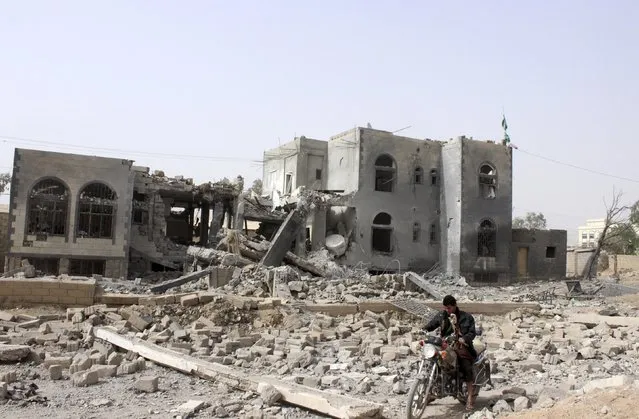 A man rides a motorcycle past a headquarters of the Houthi group, which was destroyed after an air strike by a Saudi-led coalition, in Yemen's northwestern city of Saada April 26, 2015. (Photo by Reuters/Stringer)