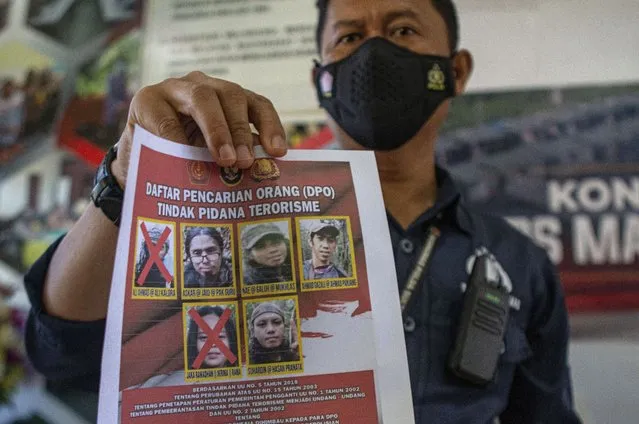 A police officer shows a wanted poster displaying the photos of two militants Ali Kalora, top left, and Jaka Ramadan, bottom left, who were killed during shootout with security forces, during a press conference at the Parigi Moutong Police Station in Parigi Moutong district, Central Sulawesi, Indonesia, Sunday, September 19, 2021. Indonesia's most wanted militant with ties to the Islamic State group was killed Saturday in a shootout with security forces, the Indonesian military said, in a sweeping counterterrorism campaign against extremists in the remote mountain jungles. (Photo by Mohammad Taufan/AP Photo)