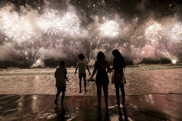 People celebrate the start of the New Year as fireworks illuminate Copacabana Beach in Rio de Janeiro, Brazil, early Monday, January 1, 2024. (Photo by Bruna Prado/AP Photo)