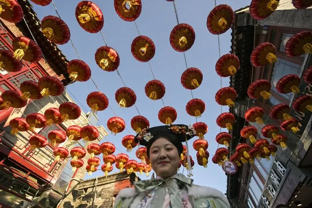 A woman wearing typical costumes smiles she walks along a street festively decorated at the Qianhai Lake tourist area in Beijing on February 7, 2024, ahead of the Lunar New Year of the Dragon which falls on February 10. (Photo by Pedro Pardo/AFP Photo)