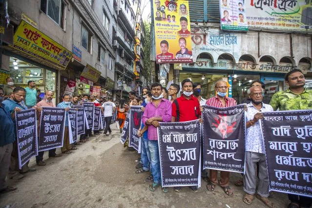 Bangladeshi Hindu community members hold banners as they take part in a protest in front of the Sri Sri Shani Dev Temple at Shankhari Bazar in Dhaka, Bangladesh, 21 October 2021. According to the police at least six people died in recent attacks on the Hindu community, temples, shops and houses in several districts in Bangladesh. (Photo by Monirul Alam/EPA/EFE)