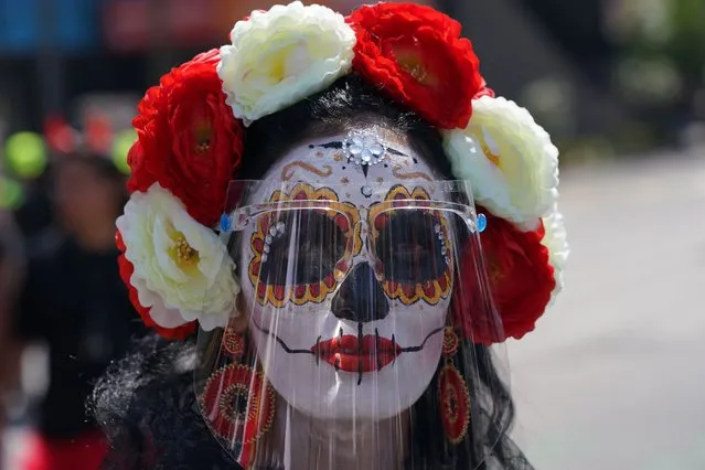 A woman made up as a “Catrina” and wearing a face shield posed for a photo during Day of the Dead festivities in Mexico City, Sunday, October 31, 2021. Altars and artwork from around the country were on display in a parade, as Mexicans honor the Day of the Dead. (Photo by Fernando Llano/AP Photo)
