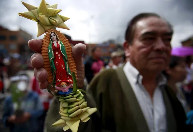 A Catholic penitent holds a religous icon decorated with a palm frond during a procession on Palm Sunday at the 20 de Julio Church in Bogota, Colombia, March 20, 2016. (Photo by John Vizcaino/Reuters)