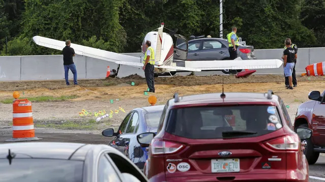 The driver, left, of a black Acura that was struck by a small plane making an emergency landing on the eastbound ramp of Maitland Blvd. to Interstate 4, surveys the damage to his car, Thursday, May 16, 2019, in Maitland, Fla. (Photo by Joe Burbank/Orlando Sentinel via AP Photo)