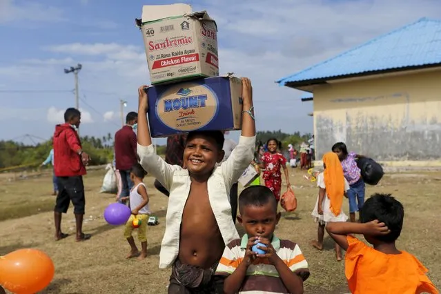 A Rohingya migrant boy, who arrived in Indonesia by boat, carry belongings as he moves to a bigger shelter with others inside a temporary compound for refugees in Kuala Cangkoi village in Lhoksukon, Indonesia's Aceh Province May 18, 2015. (Photo by Reuters/Beawiharta)