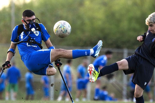 Wearing a device that measures his energy consumption, Israel Amputee Football Team player Ben Maman, left, strikes at a ball against a young soccer player, during a practice session in Ramat Gan, Israel, April 11, 2024. (Photo by Leo Correa/AP Photo)