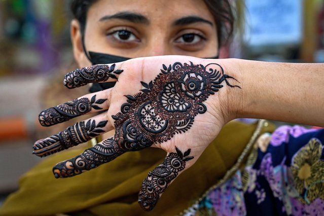 A woman poses for picture after getting her hands decorated with henna at a beauty salon in Karachi on April 8, 2024, ahead of the Eid al-Fitr festival which marks the end of the holy fasting month of Ramadan. (Photo by Asif Hassan/AFP Photo)