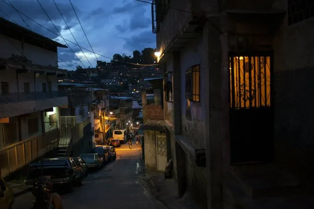 A street goes dark as the sun sets in the Petare slum of Caracas, Venezuela, Saturday, May 25, 201. When night falls, streets in Caracas clear as most residents abide by an undeclared curfew out of fear for their safety. (Photo by Rodrigo Abd/AP Photo)