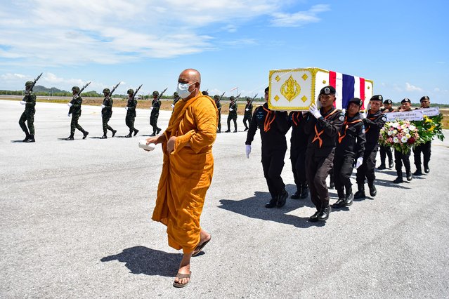 A monk walks with Thai soldiers carrying the coffins of two army rangers killed in an attack the day before, during a ceremony at Narathiwat airport in Thailand's deep south on April 9, 2024. (Photo by Madaree Tohlala/AFP Photo)