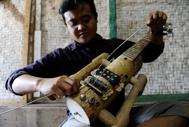Ronald Harviana (28), a bamboo artisans puts strings on a bamboo guitar at his workshop in Tanjung Wangi Village  on April 17, 2014 in Bandung, Java, Indonesia. Adang Muhidin, founder of Indonesian Bamboo Community, and his friends make sustainable bamboo musical instruments (guitar, violin, bass, trumpet, clarinet, saxophone, drums) a nod to the rise of the creative economy in Indonesia. (Photo by Robertus Pudyanto/Getty Images)