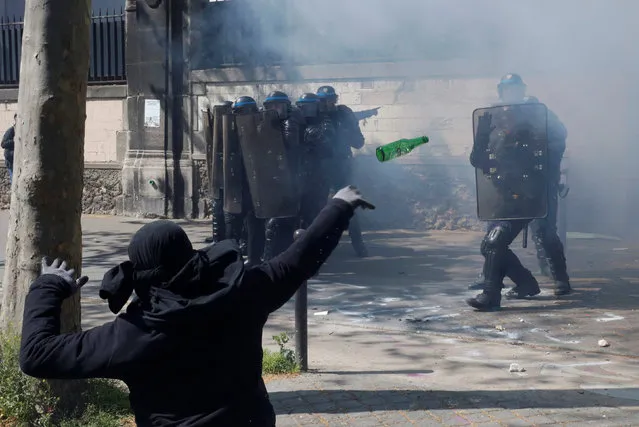 A hooded youth throws a bottle during a clash with French riot police to protest against the French labour law proposal during the May Day labour union march in Paris, France, May 1, 2016. (Photo by Philippe Wojazer/Reuters)