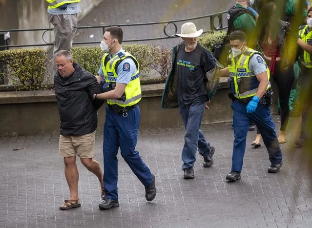 Police arrest people protesting against coronavirus mandates at Parliament in Wellington, New Zealand, Thursday, February 10, 2022. The protest began on Tuesday after more than 1,000 people driving cars and trucks from around the country converged on Parliament in a convoy inspired by protests in Canada and elsewhere around the world. (Photo by Mark Mitchell/NZ Herald via AP Photo)