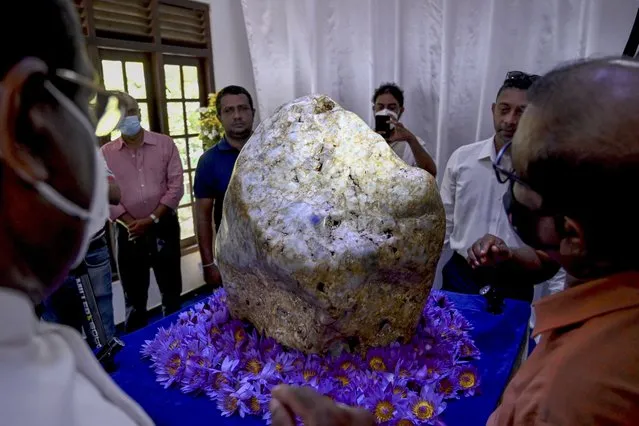 People inspect the single natural corundum (blue sapphire) named “Queen of Asia”, considered the largest found in the world, in Horana, some 45 km from Colombo on December 12, 2021. (Photo by Ishara S. Kodikara/AFP Photo)
