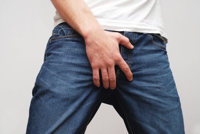 Man protecting his ballbag scrotum; man with blue jeans close up. (Photo by wakila/Getty Images)