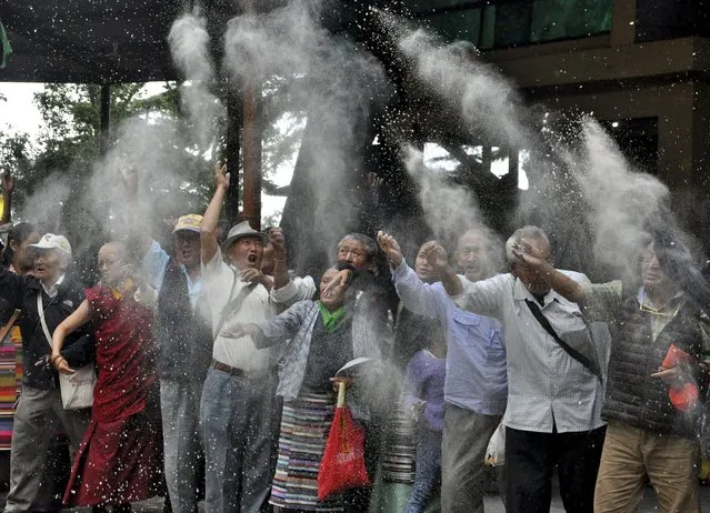 Tibetan exiles throw wheat flour into the air as part of a traditional prayer for longevity of their spiritual leader, the Dalai Lama, and world peace during celebrations marking his 80th birthday anniversary in the northern hill town of Dharamsala, India, July 6, 2015. (Photo by Reuters/Stringer)