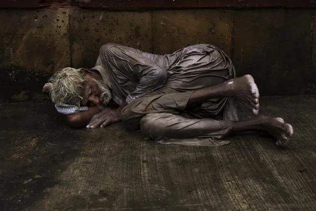 An Indian homeless man tries to sleep on a wet street during monsoon rains in New Delhi, India, Saturday, July 11, 2015. (Photo by Bernat Armangue/AP Photo)