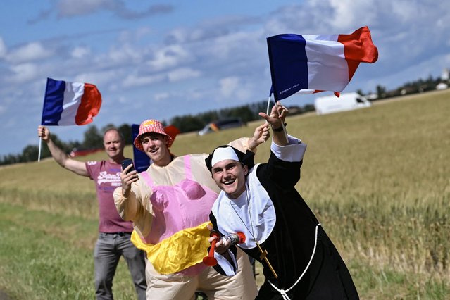 Spectators in costume wave French flags along the roadside during the 6th stage of the 111th edition of the Tour de France cycling race, 163,5 km between Macon and Dijon, on July 4, 2024. (Photo by Marco Bertorello/AFP Photo)