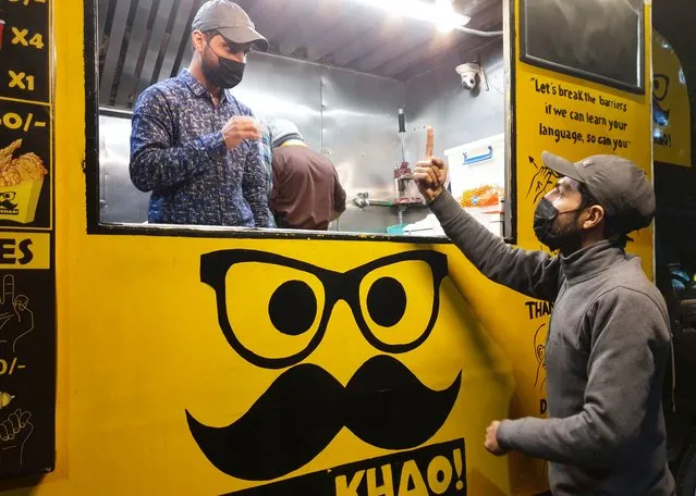 People communicate using sign language outside Pakistan's first mobile restaurant, staffed entirely by deaf workers, in Islamabad, Pakistan on February 23, 2022. (Photo by Salahuddin/Reuters)