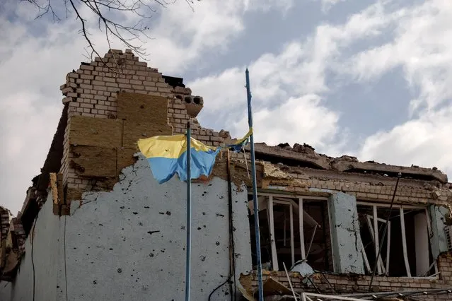 The Ukrainian flag flies outside the town administration building that was damaged during heavy shelling in the town of Derhachi outside Kharkiv, as Russia's attack on Ukraine continues, in Ukraine, April 6, 2022. (Photo by Thomas Peter/Reuters)