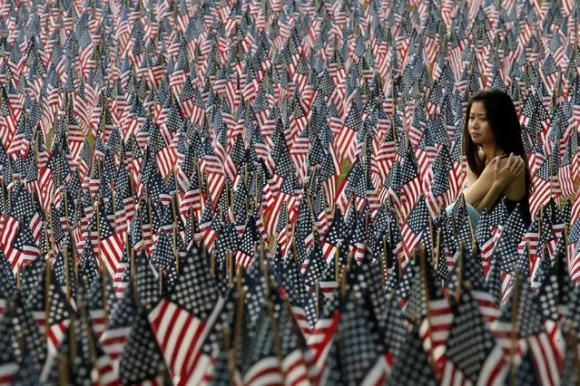 A woman sits at the edge of the field of United States flags displayed by the Massachusetts Military Heroes Fund on the Boston Common in Boston, Massachusetts, U.S. May 26, 2016 ahead of the Memorial Day holiday on May 30. The 37,000 U.S. flags are planted in memory of every fallen Massachusetts service member from the Revolutionary War to the present. (Photo by Brian Snyder/Reuters)